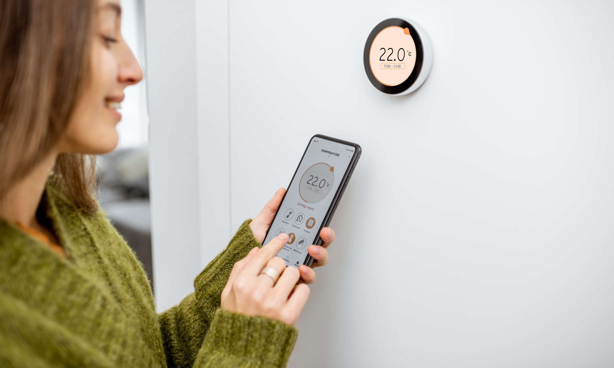 Woman programming home heating system to a consistent temperature to promote comfort and efficiency.
